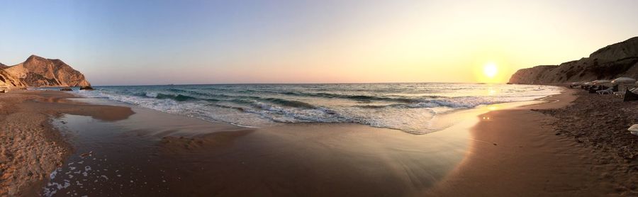 Scenic view of beach against sky at sunset