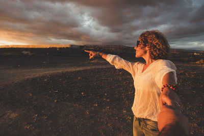 Young woman standing on landscape against sky