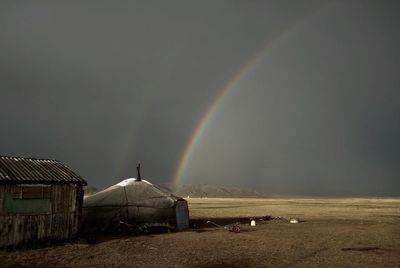 Scenic view of rainbow over field against sky