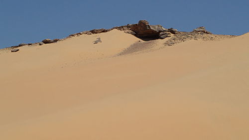 Low angle view of sand dunes against clear sky