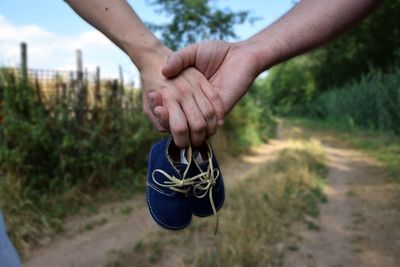 Close-up of man hand holding plant on field