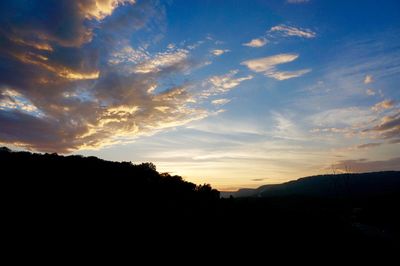 Silhouette of mountain against cloudy sky at sunset