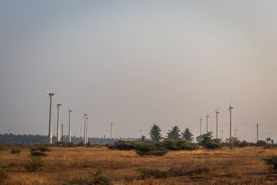 Wind turbines on field against clear sky