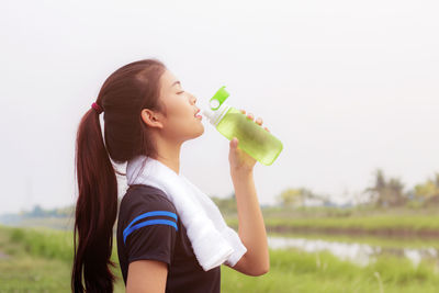 Side view of young woman drinking water