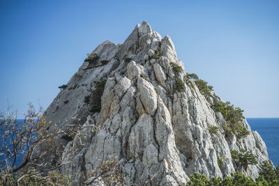 Rock formations in sea against clear blue sky