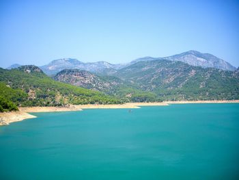 Scenic view of sea and mountains against clear blue sky