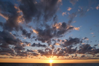 Scenic view of sea against dramatic sky during sunset