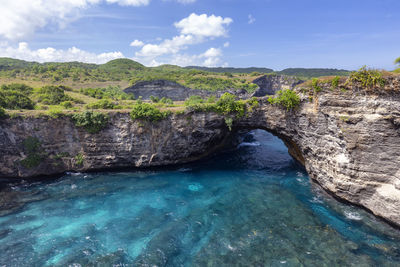 Scenic view of rock formation in sea against sky