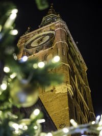 Low angle view of illuminated christmas tree against building at night