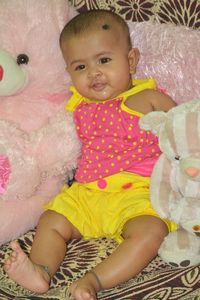 Portrait of cute baby girl lying on bed