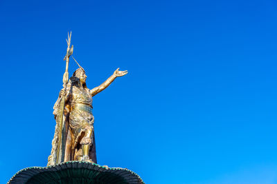 Low angle view of pachacuti statue against clear blue sky at plaza de armas