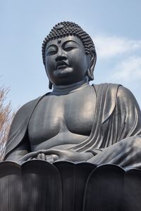 Low angle view of buddha statue against sky