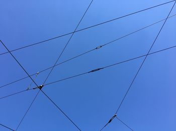 Low angle view of power lines against clear blue sky