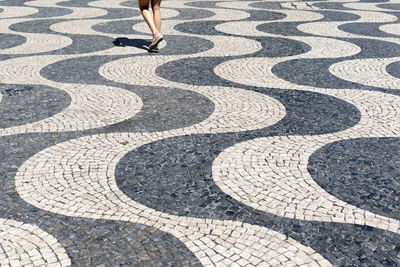 Surface of traditional cobble stone pavement in lisbon, portugal. person walking on footpath 