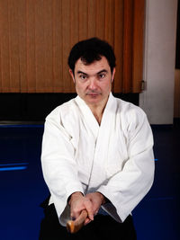 Portrait of man holding wooden sword on tatami mat