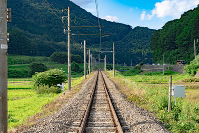 Railroad track by mountain against sky