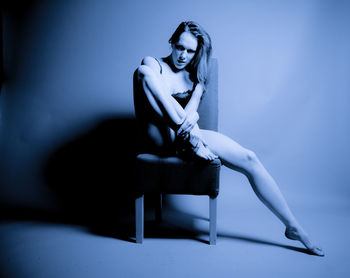 Portrait of woman sitting on chair against white background