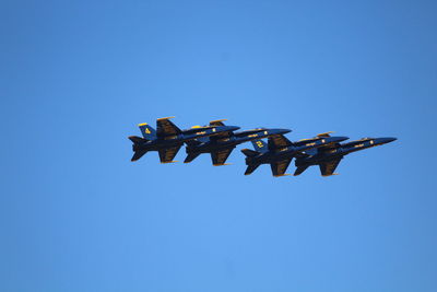 Low angle view of airplane flying against clear blue sky