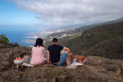 Young couple at picknic at view point with amazing overview over shoreline of tenerife.