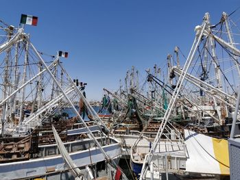 Fishing boats moored at harbor against clear sky