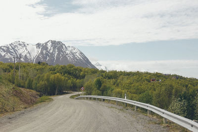 Scenic view of country road by mountain against sky