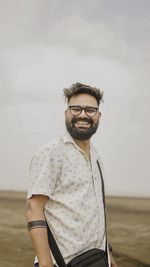 Portrait of young man standing against sky