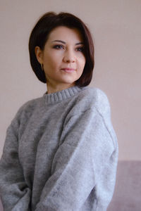 Portrait of young woman standing against wall