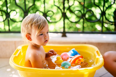 Girl with toys sitting in bathtub