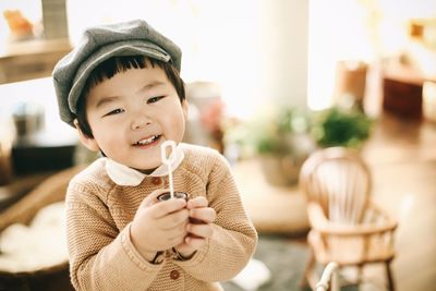 Portrait of cute boy holding camera at home