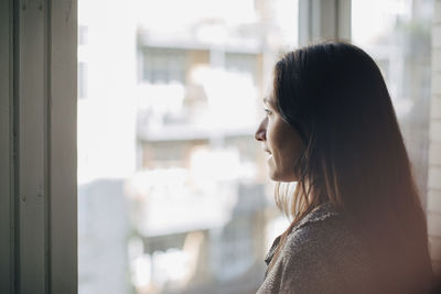 Portrait of woman looking through window