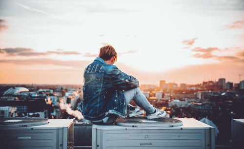 Rear view of man looking at cityscape against sky