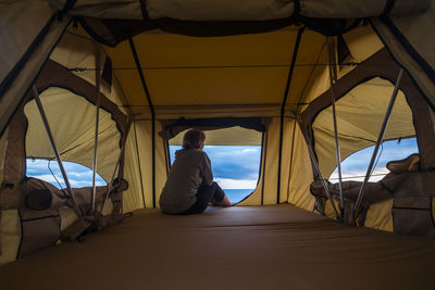 Rear view of mature woman sitting in tent