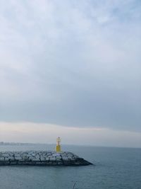 Lighthouse by sea against sky