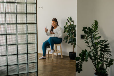 Full length of young woman standing against wall