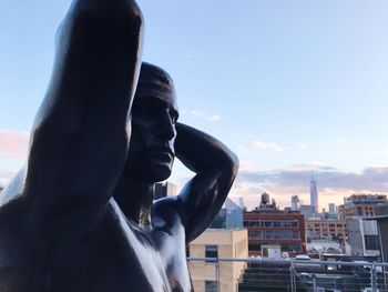 Statue against buildings in city against sky