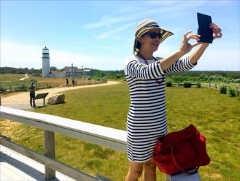 Woman taking selfie against lighthouse