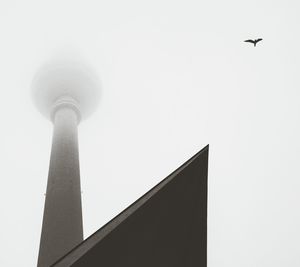 Low angle view of fernsehturm and building against clear sky