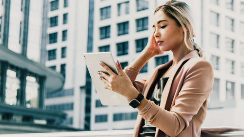 Young woman using digital tablet in city