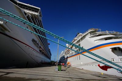 Low angle view of ship moored at harbor against clear blue sky