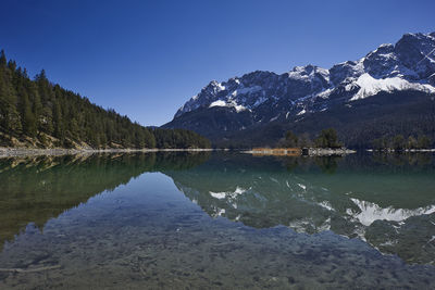 Scenic view of lake and mountains against clear blue sky