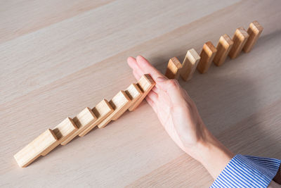 Cropped hand of man holding wooden blocks on table
