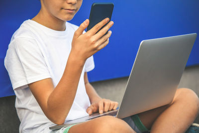 Boy using phone and laptop