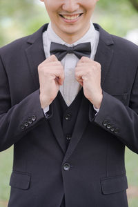 Midsection of businessman wearing tuxedo while standing outdoors