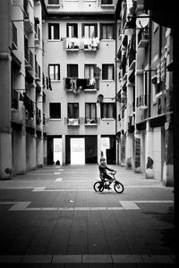 Man riding bicycle on street amidst buildings in city