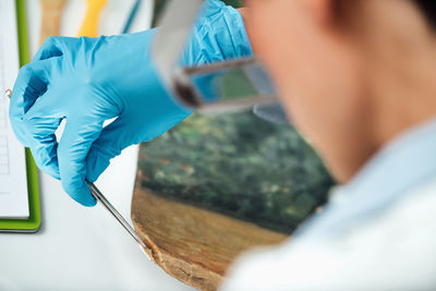 Female conservator with magnifying goggles cleaning dirt from antique oil painting