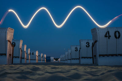 Light trails on beach against sky at night