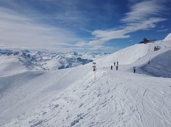 People skiing on snowcapped mountain against sky