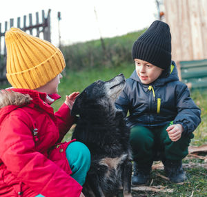 Happy children in autumn clothes squatting and petting a dog. friendship and care for animals.