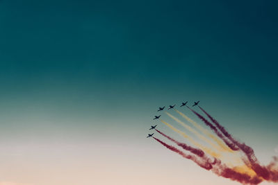 Low angle view of airshow against clear blue sky