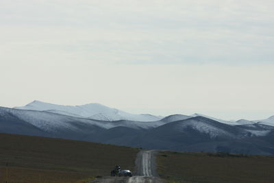 Cars on road by snowcapped mountains against sky